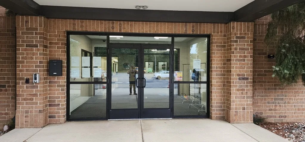 Black-framed double glass entry doors set in a brick commercial entrance in Jackson, MI.