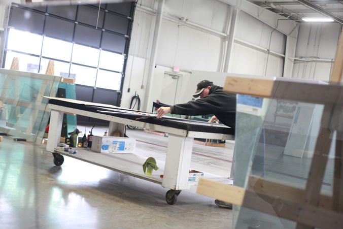 Auto glass technician working beside windshields in the Jackson Glass Works shop